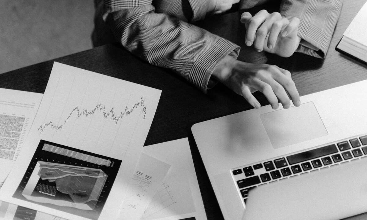 Une personne travaille sur un ordinateur portable, entourée de documents