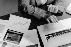 Une personne travaille sur un ordinateur portable, entourée de documents