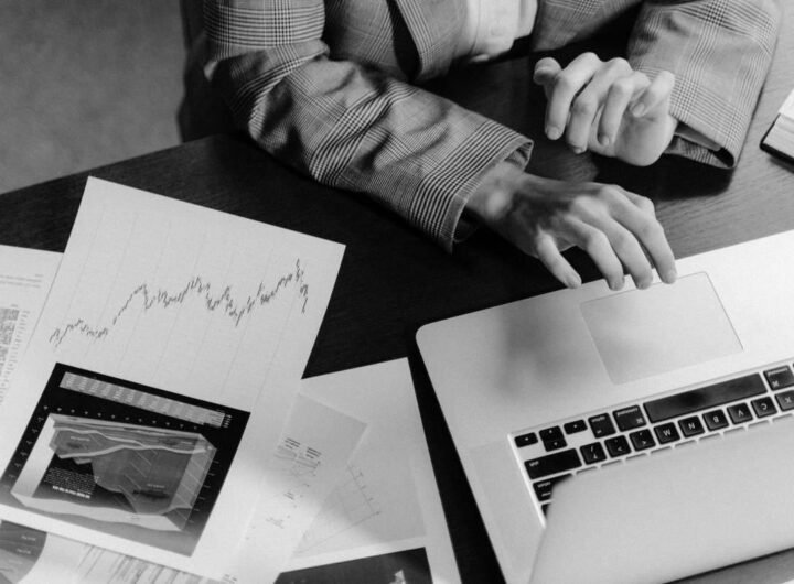 Une personne travaille sur un ordinateur portable, entourée de documents