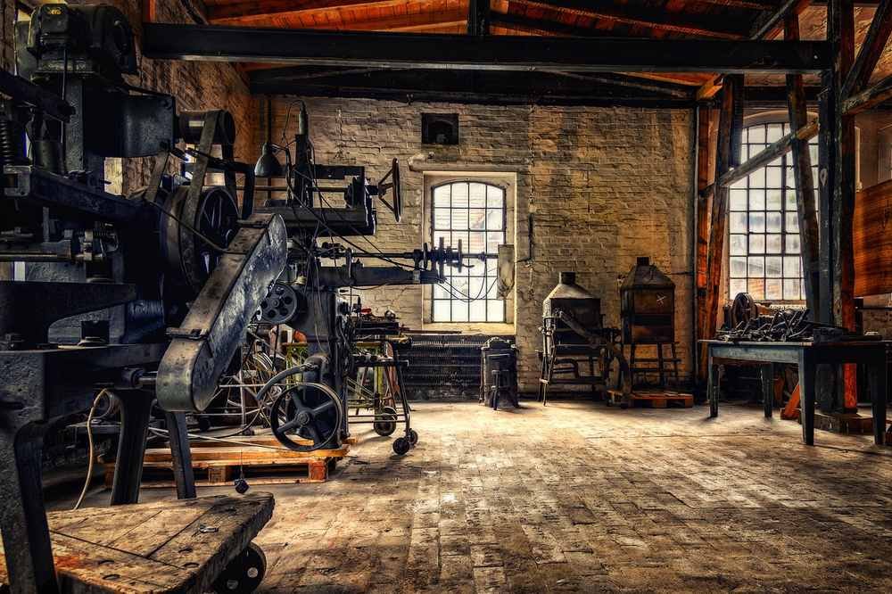Ancien atelier industriel avec machines, briques, fenêtres et sol en bois