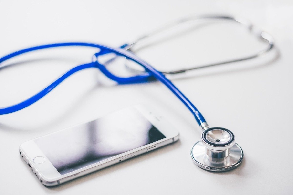 Stéthoscope et smartphone posés sur une surface blanche